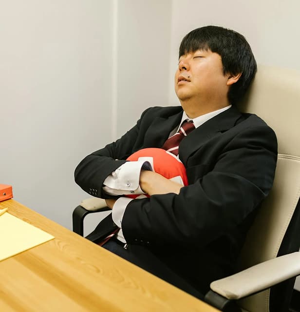 image of a formally dessed man sleeping on an office desk